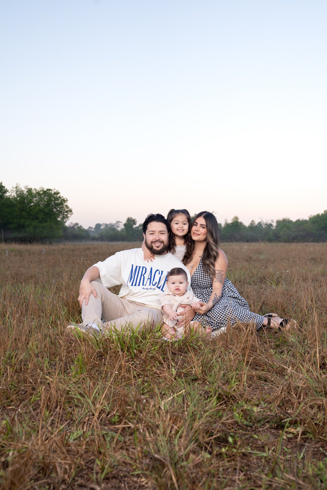 Esteban with his wife and their two young children in a field at sunset
